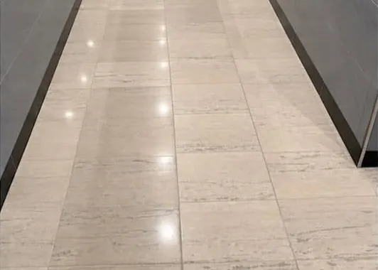 The same corridor tile floor after restoration, with a clean, reflective finish