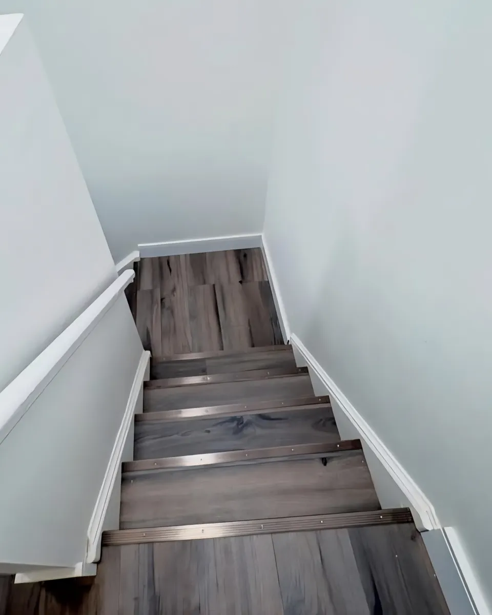 Renovated residential stairwell with fresh white walls, new trim and wood-look flooring with metal stair nosings